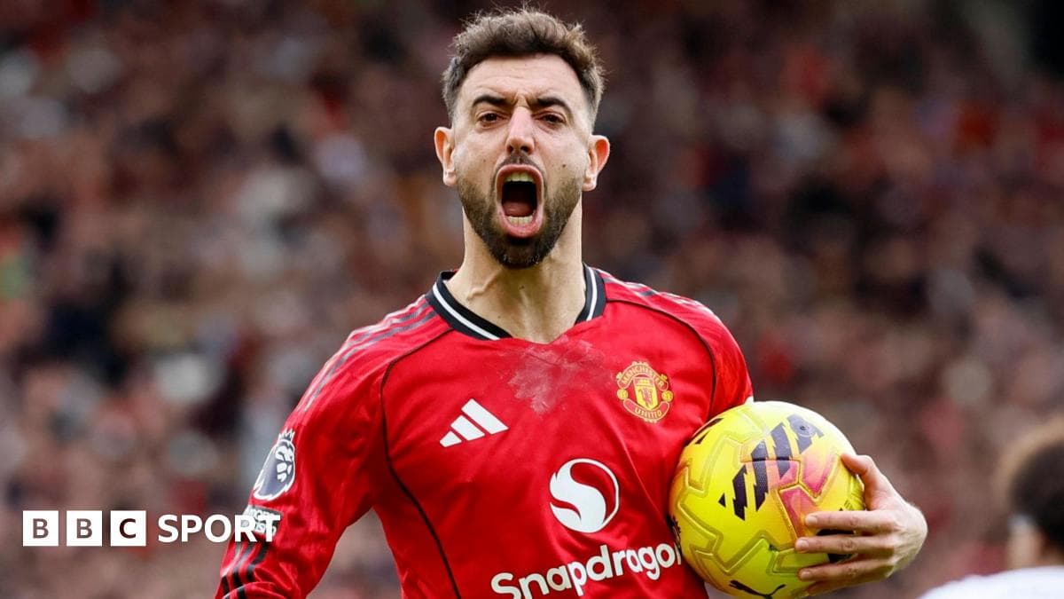 Futbolçu qırmızı forma ilə topu tutaraq sevinir