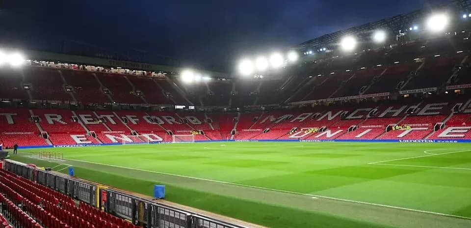Old Trafford stadium with empty seats and illuminated pitch