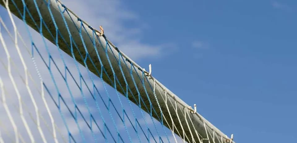 Close-up of a goalpost net against blue sky