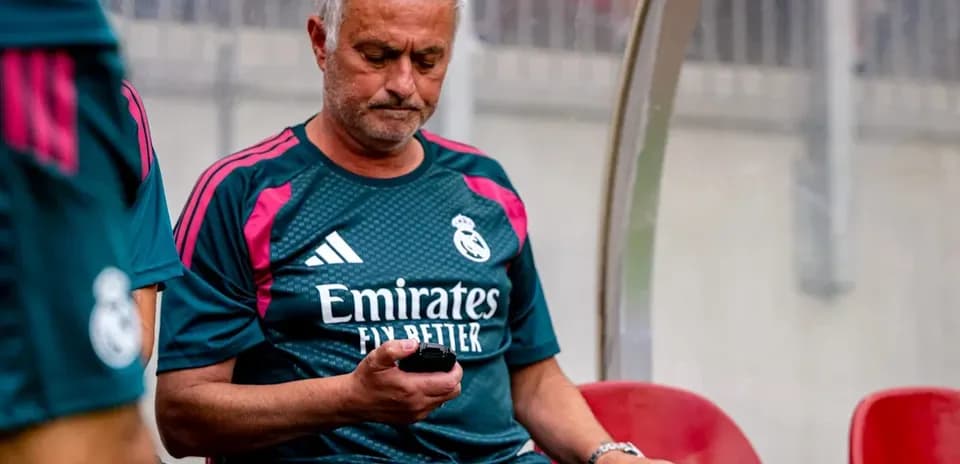Coach sitting on bench looking at mobile phone