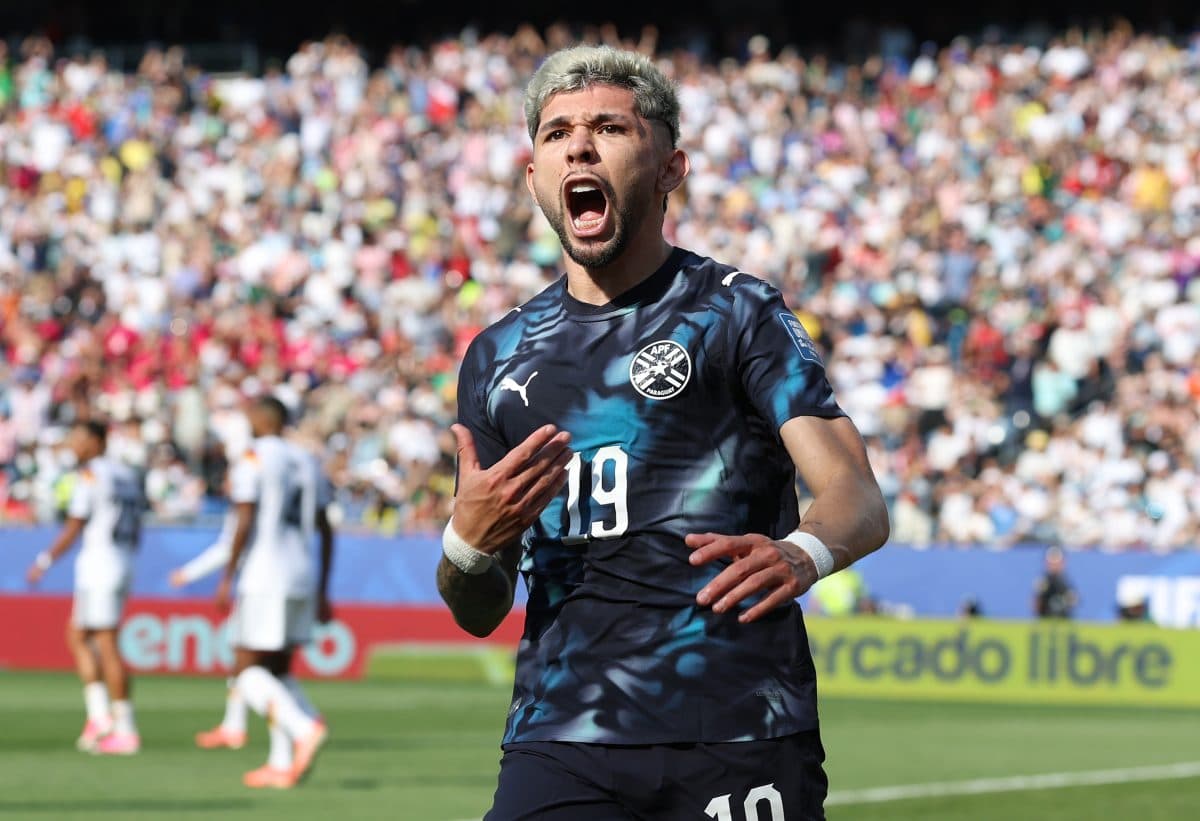 Futbolçu qolu qeyd edərək sevinir, arxa planda azarkeşlər