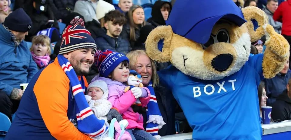 Fan group posing with mascot at football match