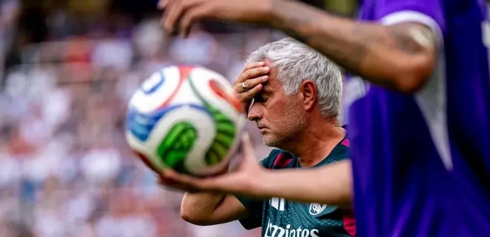 Coach holding forehead during match with soccer ball
