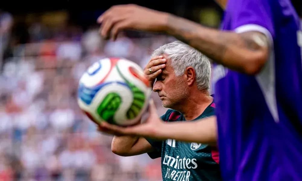 Coach holding forehead during match with soccer ball