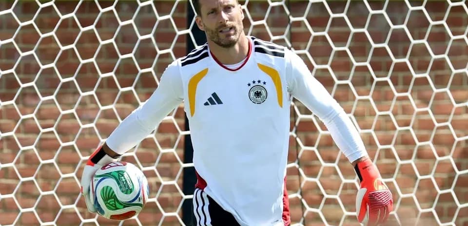 Goalkeeper holding ball in front of goal net