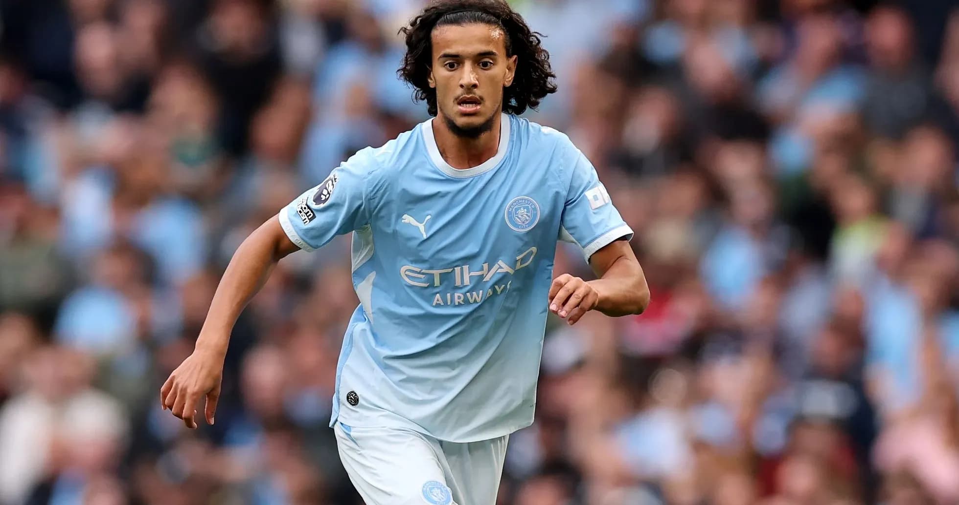 Futbolçu Manchester City formasında topa doğru irəliləyir