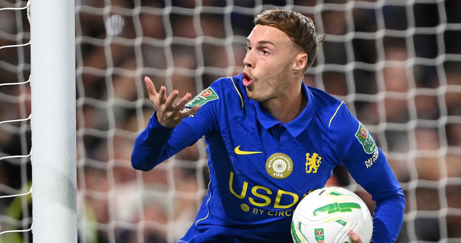 Chelsea player gesturing while holding the ball