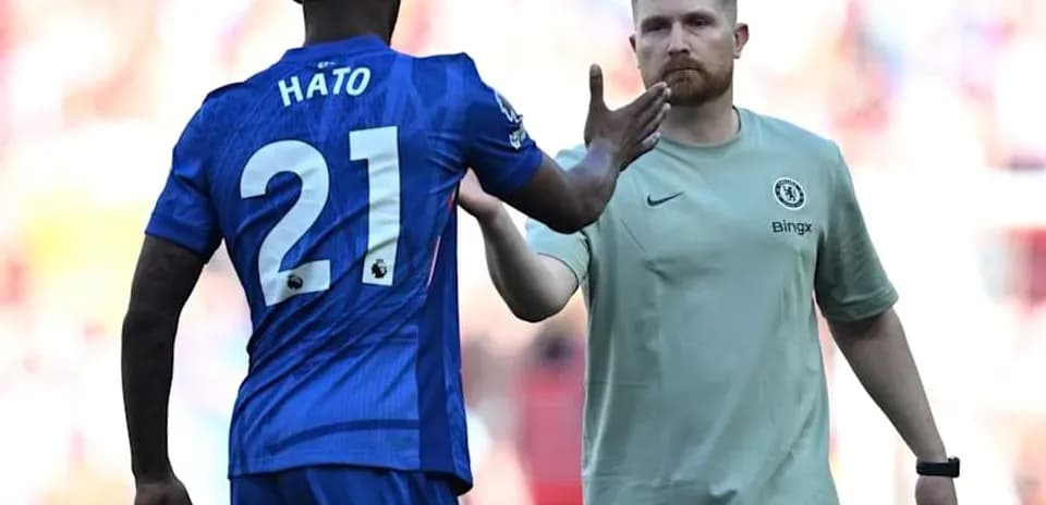 Player in blue jersey greeting coach on the field