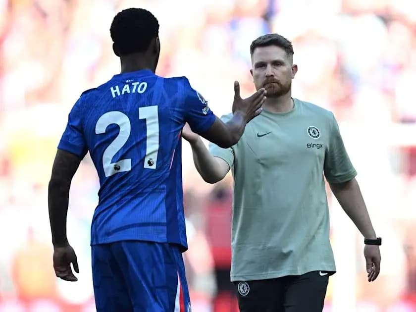 Player in blue jersey greeting coach on the field