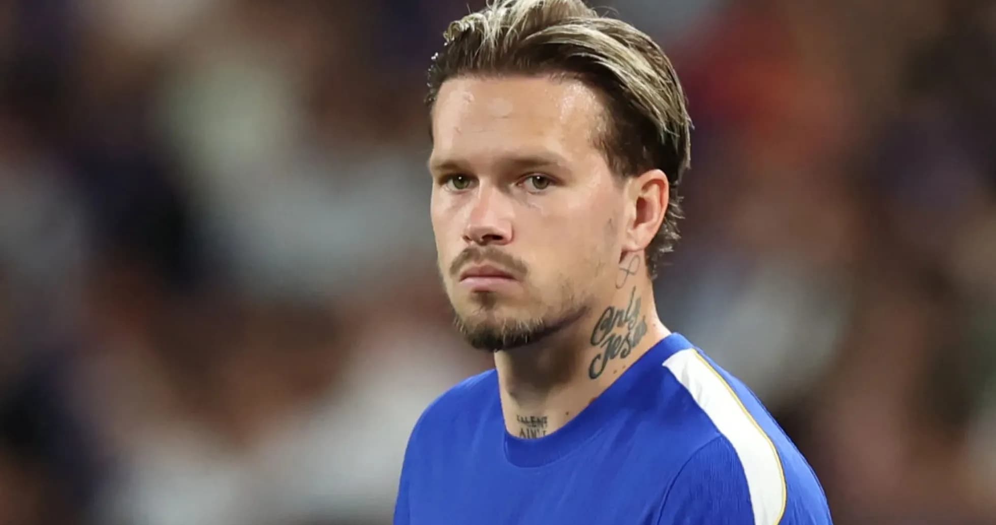 Futbolçu mavi forma ilə meydanda durur