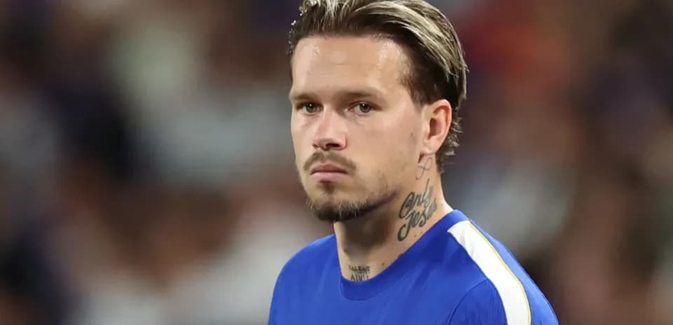 Futbolçu mavi forma ilə meydanda durur