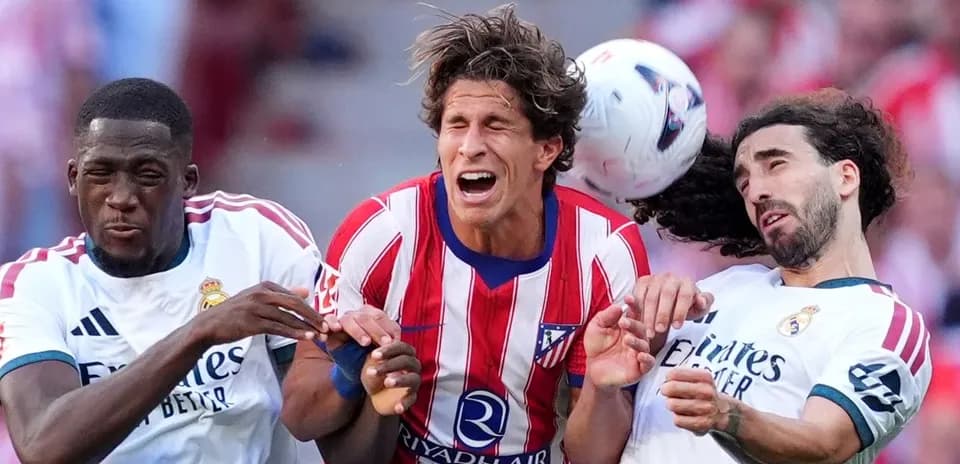 Atletico and Real Madrid players competing for the ball
