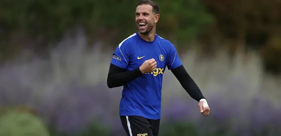Futbolçu mavi forma ilə gülərək məşq edir