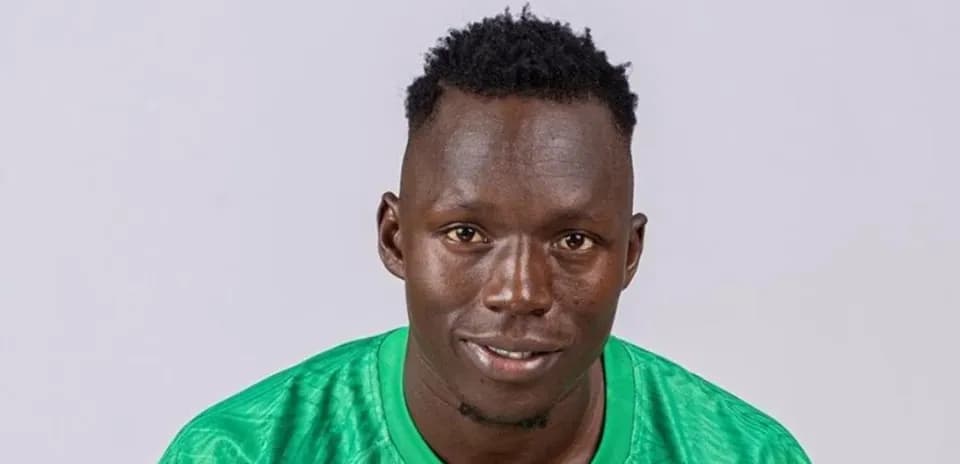 Goalkeeper posing in green jersey against plain background