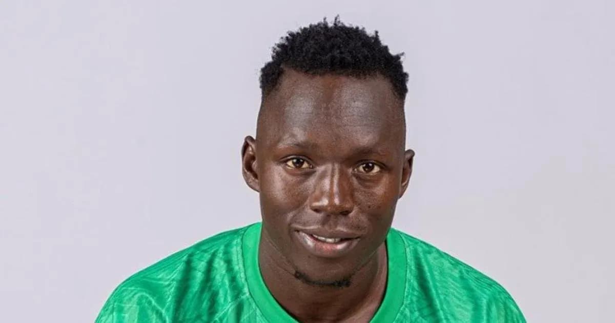 Goalkeeper posing in green jersey against plain background
