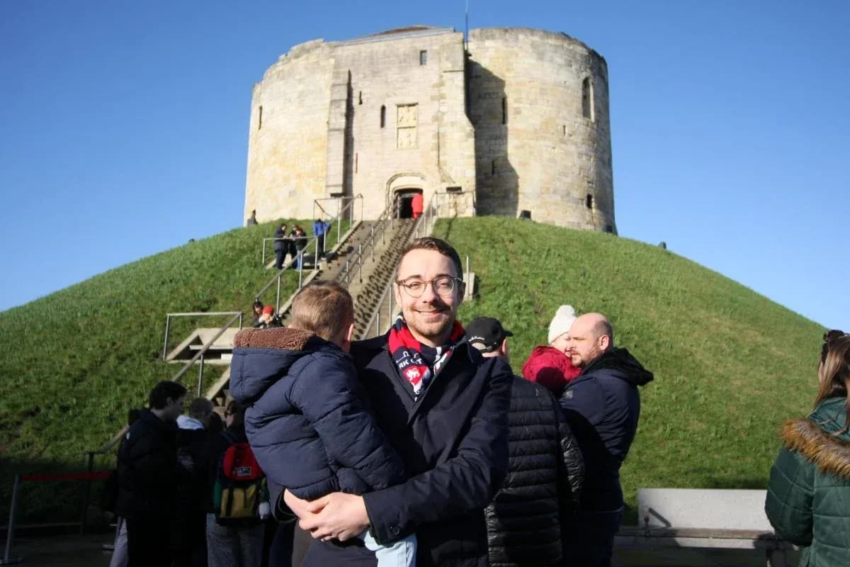 Man holding a child in front of a historic tower