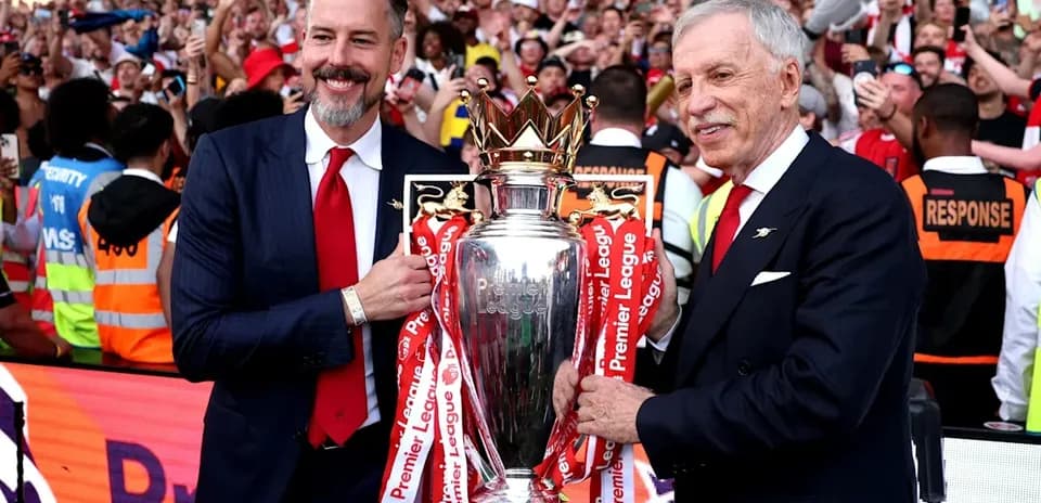 İki kişi Premier League kubokunu tutaraq azarkeşlərə təqdim edir