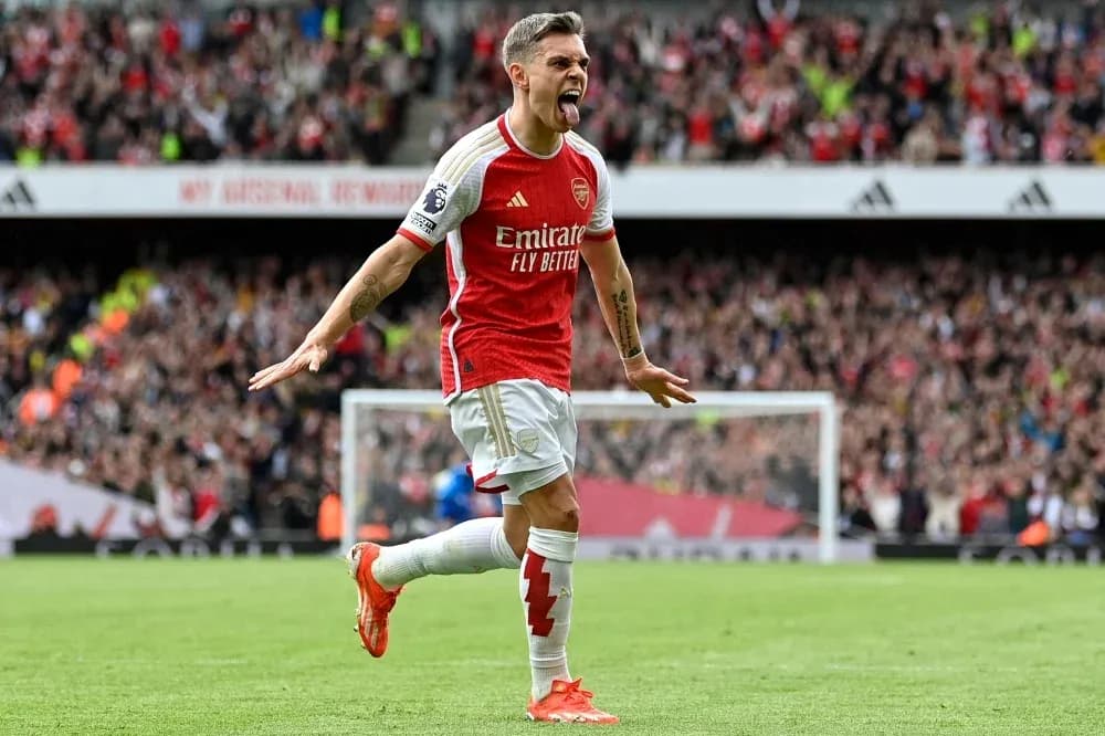 Futbolçu qolu qeyd edir, Arsenal azarkeşləri arxada Futbolçu qolu qeyd edir, Arsenal azarkeşləri arxada