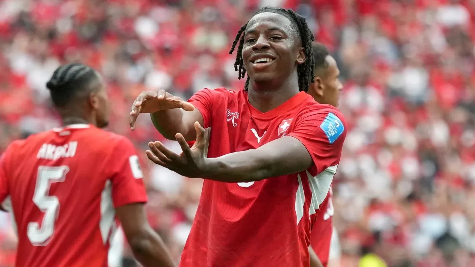 Futbolçu qol sevincini paylaşır, arxa planda komanda yoldaşları Futbolçu qol sevincini paylaşır, arxa planda komanda yoldaşları