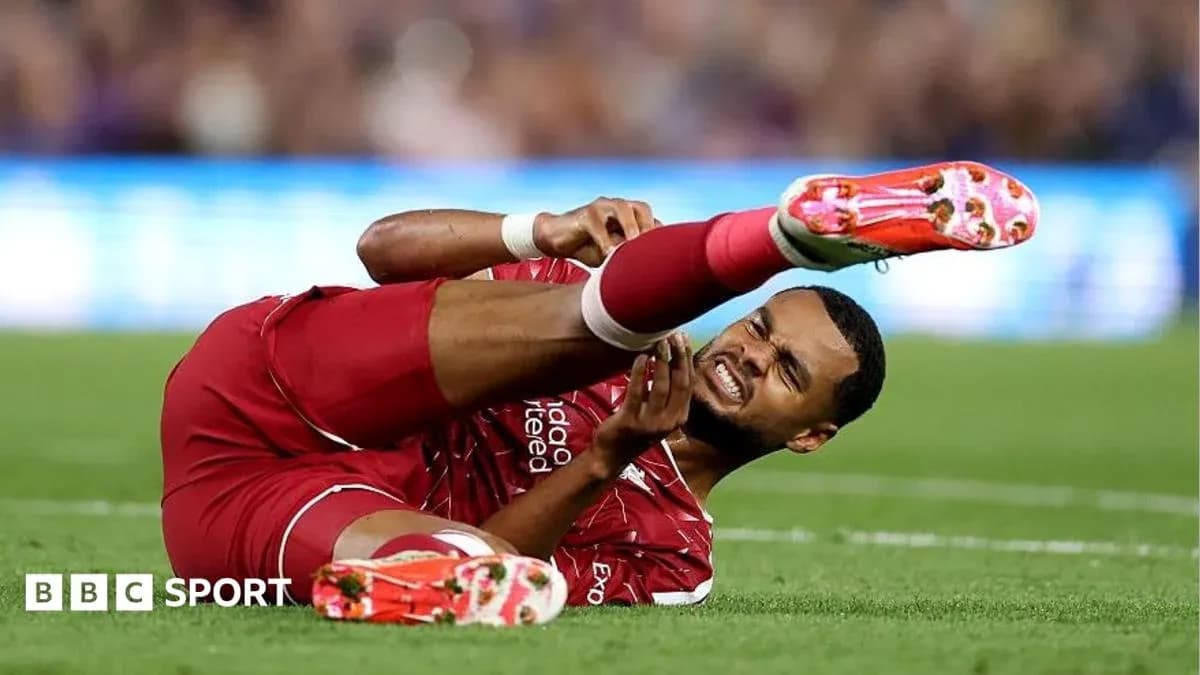 Player in red kit lying injured on the field Player in red kit lying injured on the field