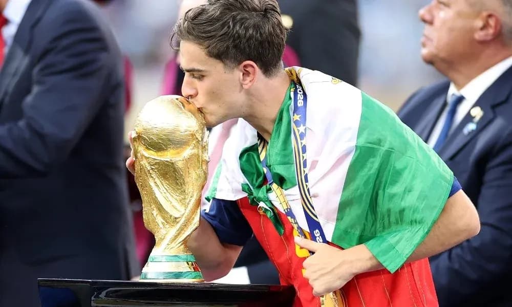 Player kissing World Cup trophy while draped in flag Player kissing World Cup trophy while draped in flag