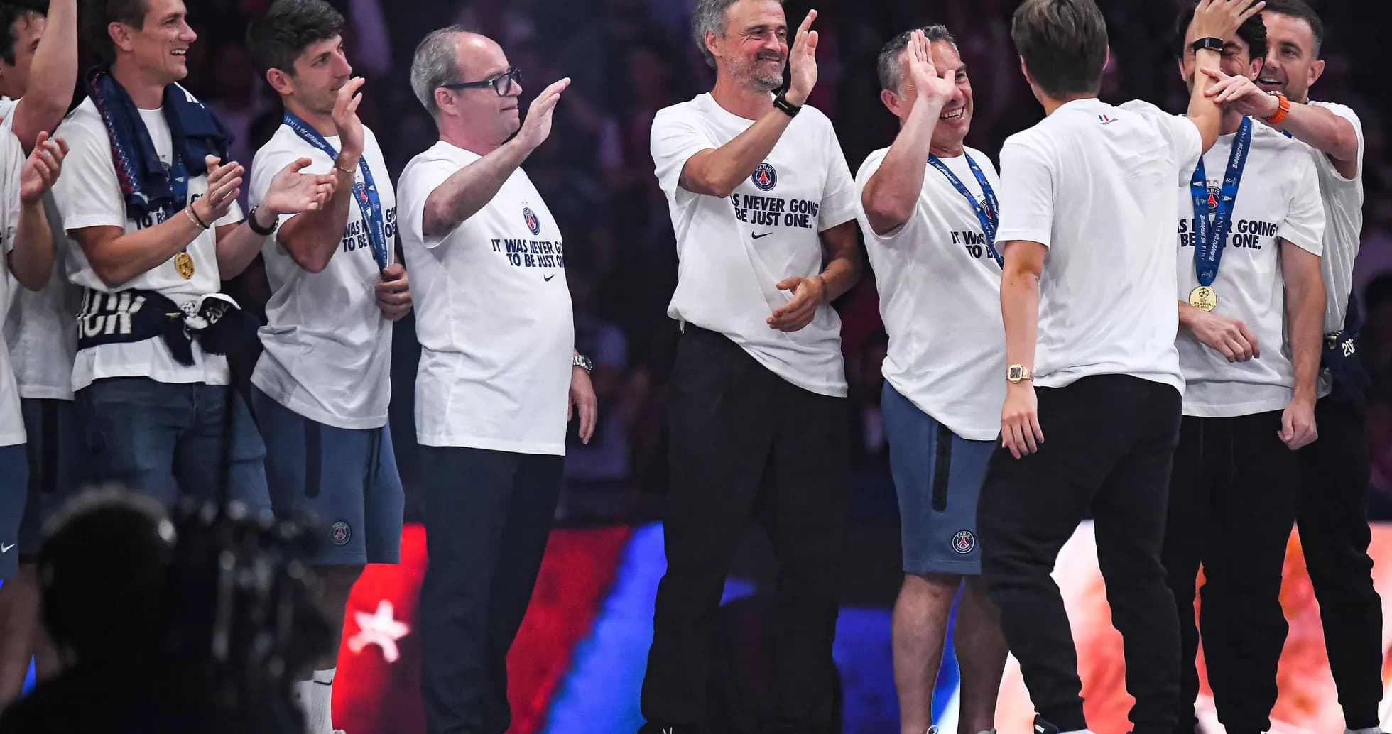 Coaching staff celebrating with medals on stage Coaching staff celebrating with medals on stage