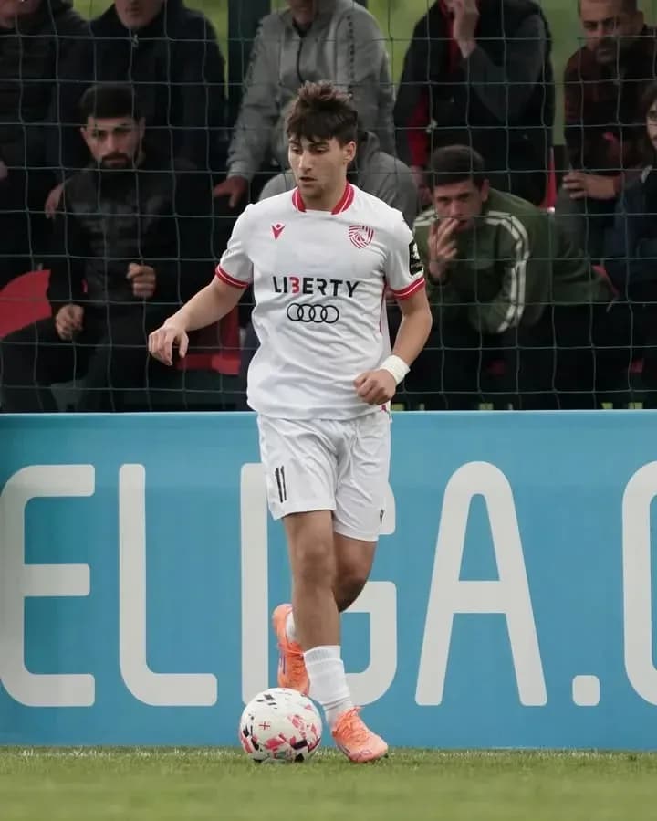 Futbolçu topu idarə edir, arxa planda azarkeşlər var Futbolçu topu idarə edir, arxa planda azarkeşlər var