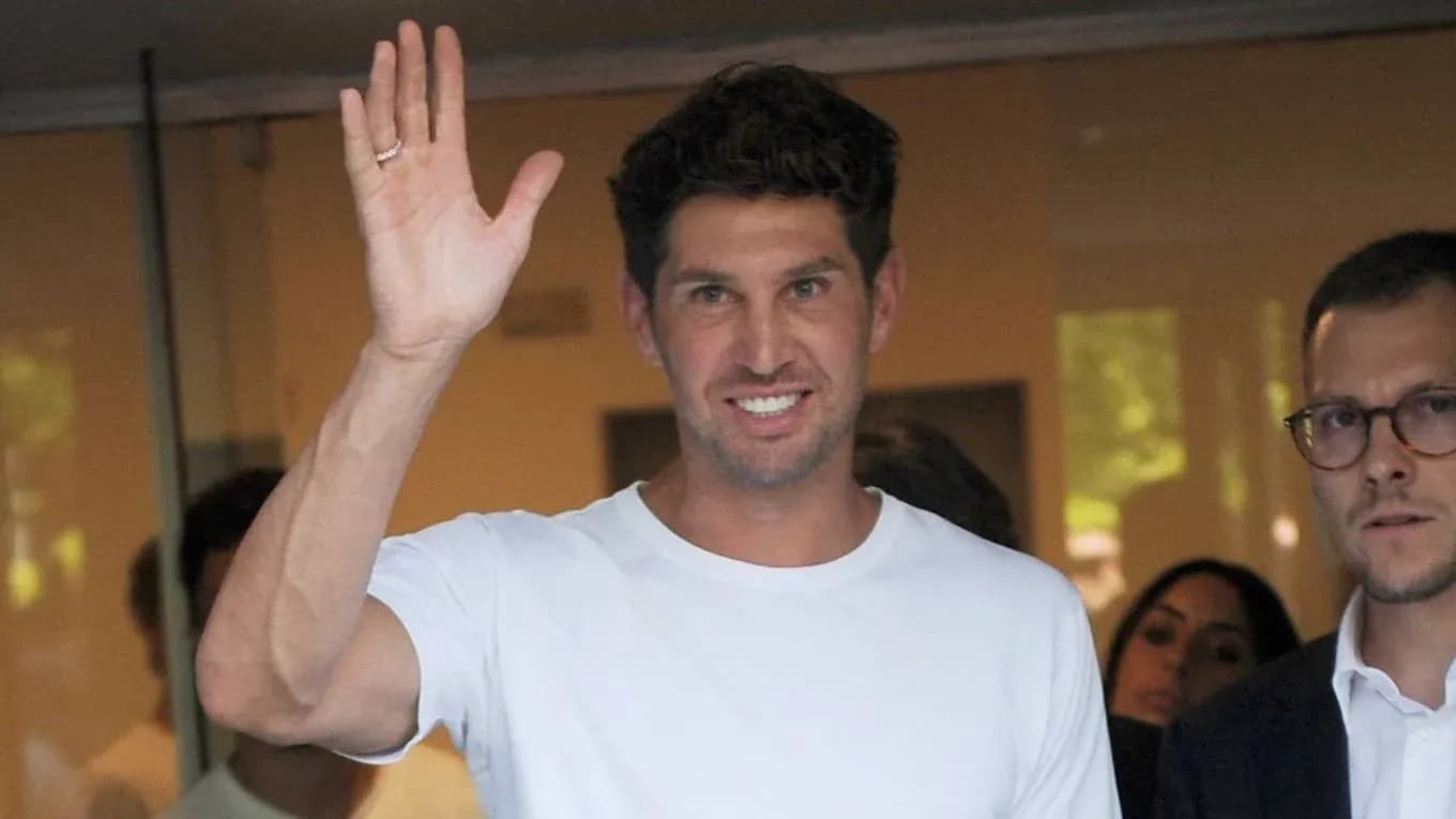 A man waving while standing in an office entrance A man waving while standing in an office entrance