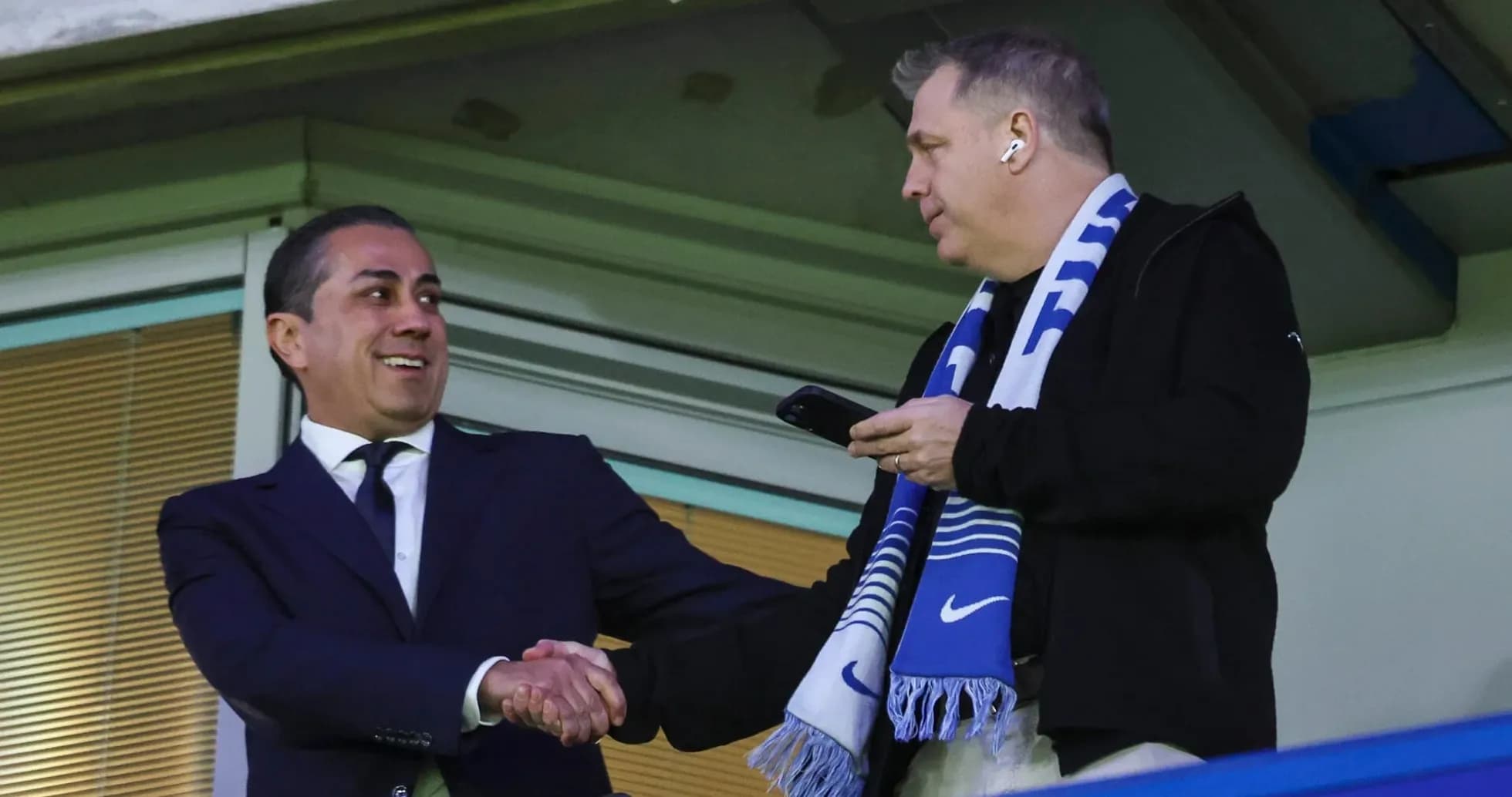 Two men shaking hands in stadium box Two men shaking hands in stadium box