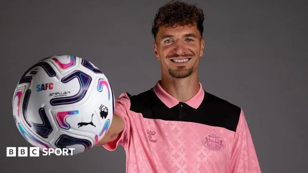 Futbolçu topu göstərərək gülümsəyir Futbolçu topu göstərərək gülümsəyir