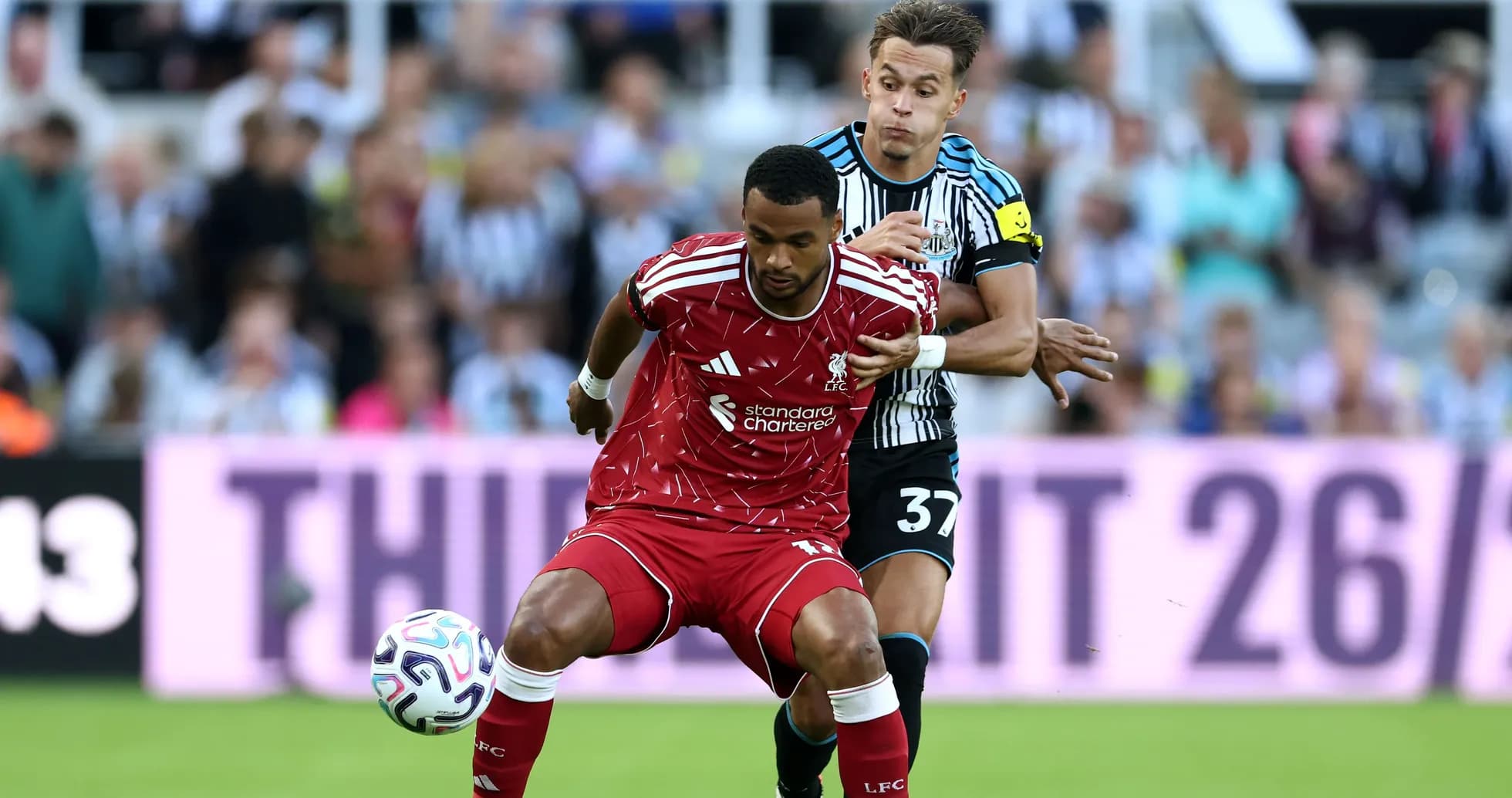 Liverpool player being challenged by Newcastle opponent Liverpool player being challenged by Newcastle opponent