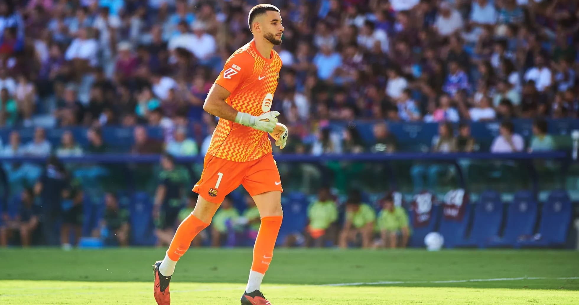 Goalkeeper in orange kit running on the pitch Goalkeeper in orange kit running on the pitch