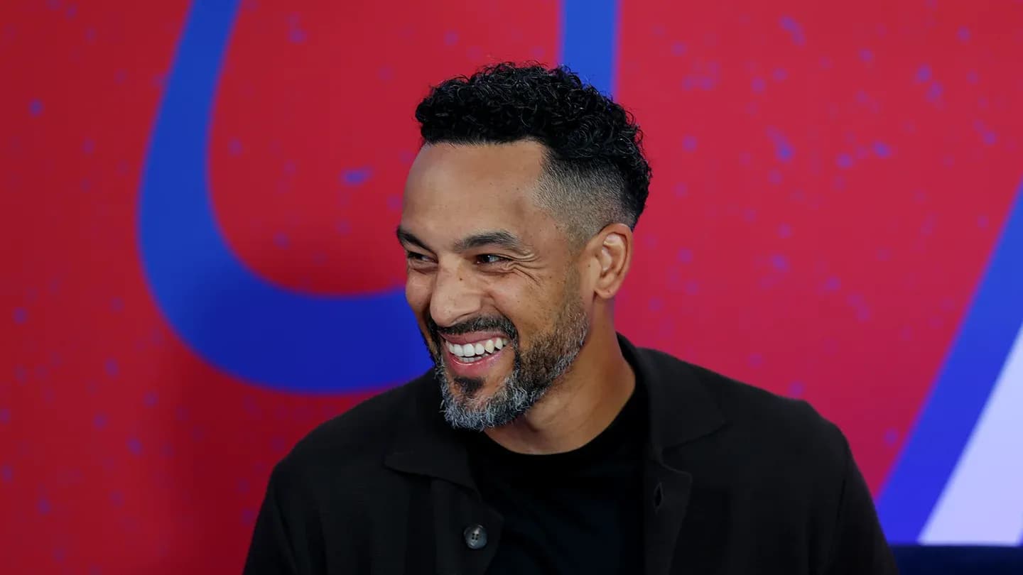 Man smiling during an interview on stage Man smiling during an interview on stage
